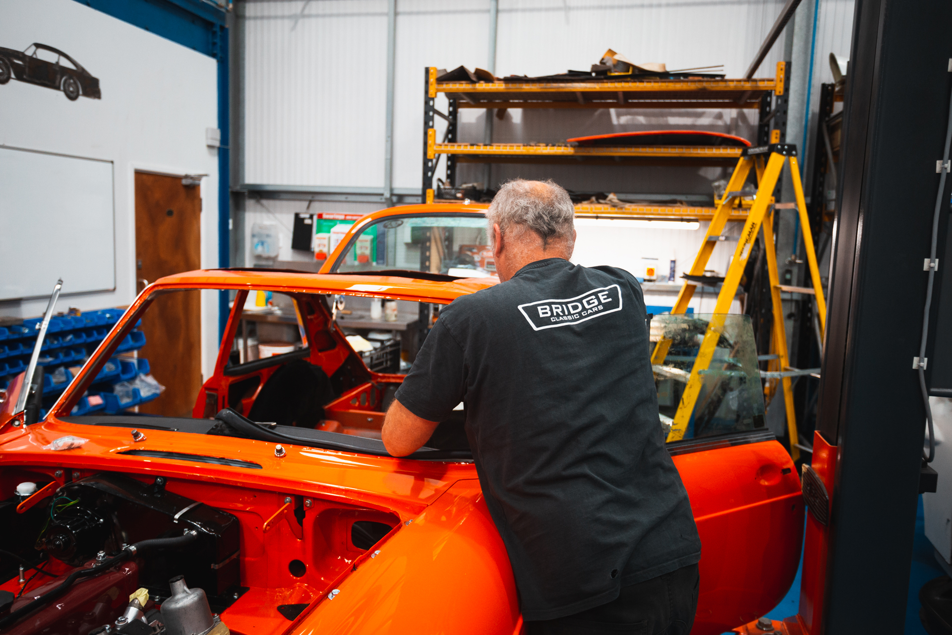 A classic car technician working on an MG B GT